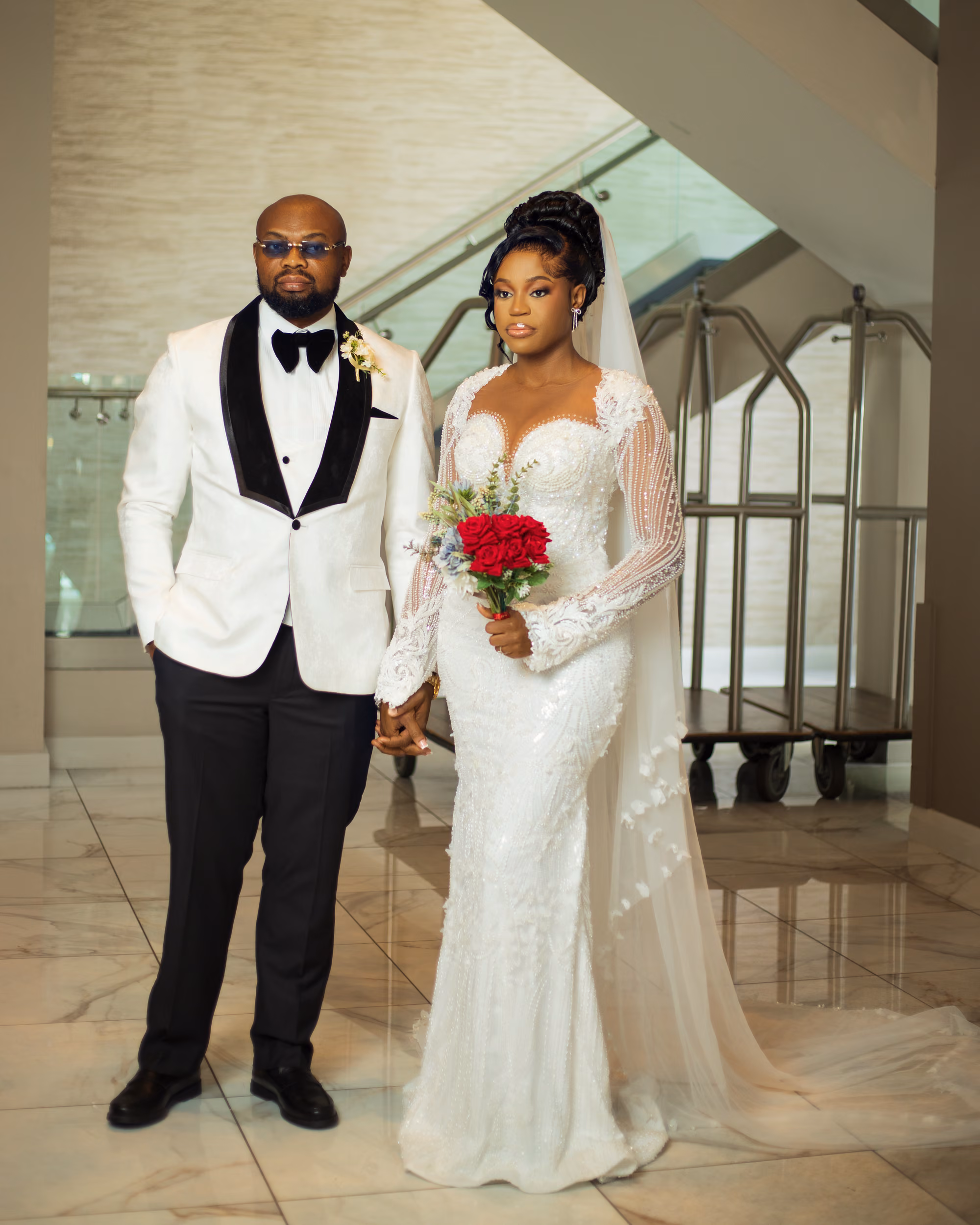 A couple in wedding attire walk through a decorated corridor.