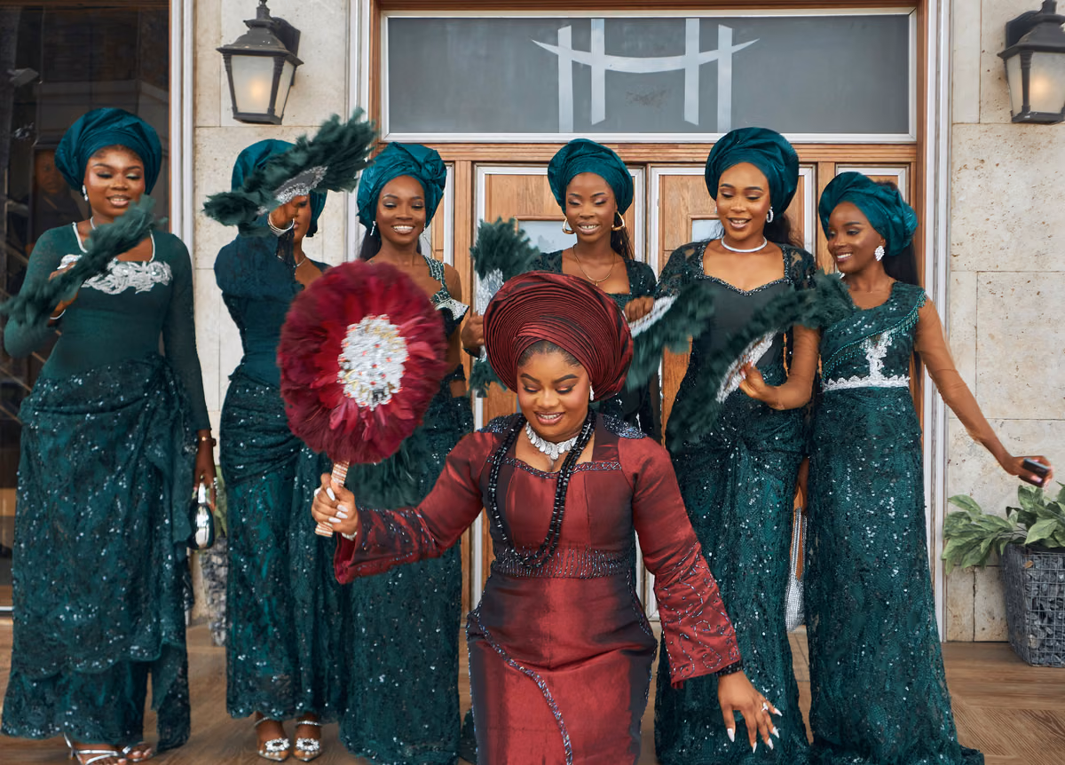A bride and wedding party gather beneath a decorated entrance.